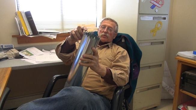 VerMod exec Chet Pasho explains the use of a company-devised insulation density sampling device, cut from a section of vent pipe. The teeth on the end of the tube allow the inspector to bore into the insulated wall and extract a measured volume of insulation, which is then weighed to calculate density of the material as installed. Walls are tested at several points during construction to ensure uniform quality of insulation density.