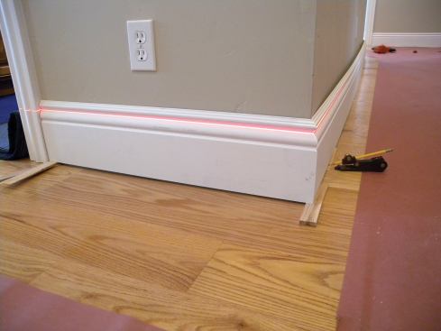 We use laser levels to find the high points in a room and to establish a level line to work to. We shoot the reference line even with the top of the baseboard or align it with a fillet in the profile.