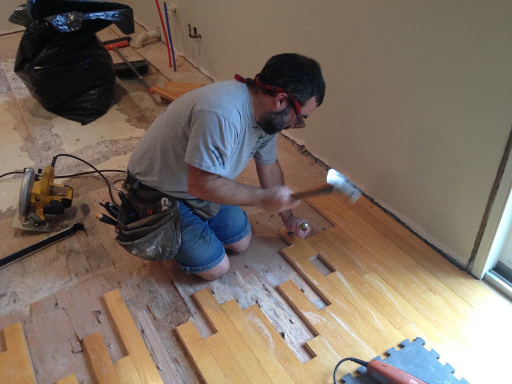After rough cutting the boards, a few need to be removed back to an existing seam. One way is to slide the board out. Manny buries the blade of a chisel in the piece to be removed and then strikes the chisel to loosen the board and slide it out. If there are too many nails holding the board, another method has to be used.