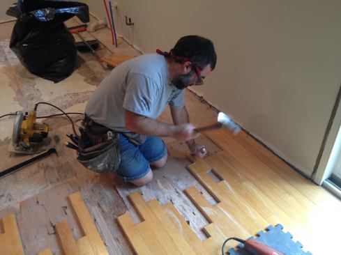 After rough cutting the boards, a few need to be removed back to an existing seam. One way is to slide the board out. Manny buries the blade of a chisel in the piece to be removed and then strikes the chisel to loosen the board and slide it out. If there are too many nails holding the board, another method has to be used.
