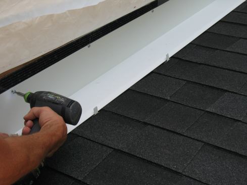 Mike avoids driving fasteners through the roof leg by using clips made from scraps of flashing metal to secure the outside edge. The clips are folded in the middle and fasten through the roof shingles in line with the outside edge of the continuous flashing every 16 inches or so.