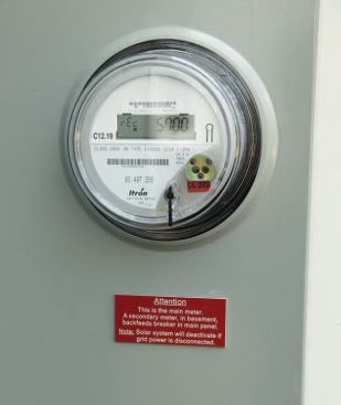 A digital electric meter displays a constant readout of power delivered to and from the grid.