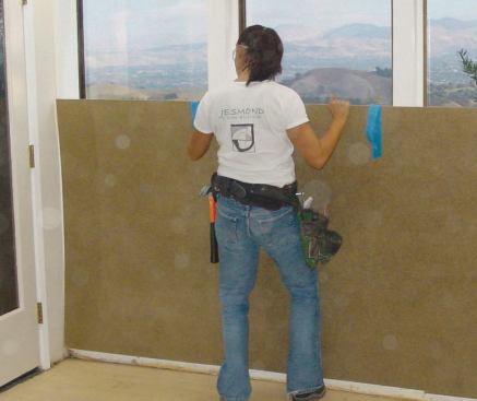 The windows are then covered with sheets of hardboard that rest on the screws at the bottom and are taped to the wall along their upper edges.
