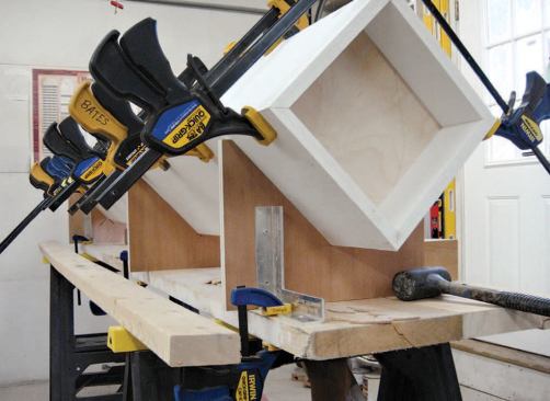 Plywood gluing cradles, accurately sized to match the tapering columns, make it easy to place the clamps.