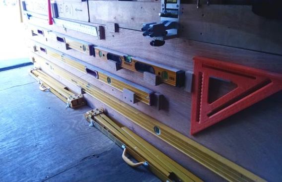 Long items, such as levels, store on the side of the console that houses the portable bench. If you look closely you’ll see the L-shaped clips that prevent the folding horses from sliding around on the floor.