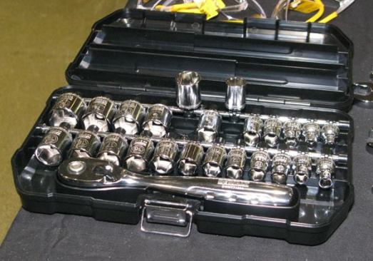 The case is hinged at the back and has metal latches at the front. Sockets slip onto fittings that pivot out from the case, which makes it easier to keep them organized and prevents them from falling out.