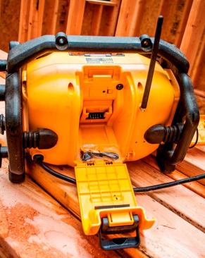 The DCR015 can be powered by a 20V MAX battery (not shown) that fits into a compartment on the back of the housing. When the cord (lower left) is plugged in the radio can be used to charge the battery.