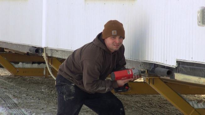 Tyler Boice unbolts the modular unit base from the trailer rig after arriving at the home site.