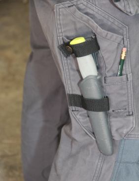 The sheath fits through a loop on the pants—which keeps it from swinging or flopping around. The knife “clicks” into the sheath and should not fall out. As an added measure, these pants include a piece of webbing that snaps around the end of the hilt. This particular knife and sheath are made by Mora.