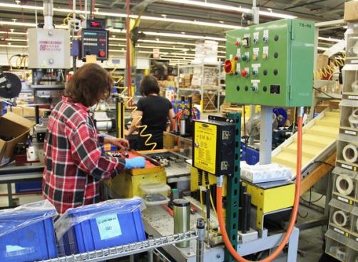 This gal is assembling screwdrivers by using a press to push blades into handles. 
Click here for video.