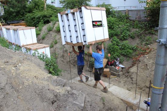 Project manager, Steve Daly, and carpenter Greg Hunt carry a bundle of foam forms into the foundation hole on site. The lightweight foam forms eased the labor of construction for the project while improving the foundation’s energy performance.