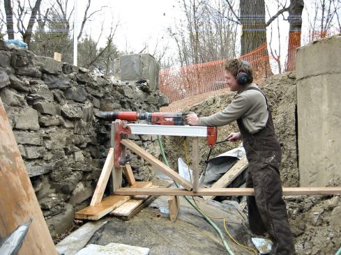 An improvised stand supports the coring drill used to bore 3-inch-diameter holes for the wall tiebacks. To provide an aiming point, a length of white closet rod - visible at top left - was inserted in the previously drilled vertical holes extending from top to bottom of the wall.