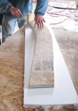 Rake Overhang: It's easier to cut curves in OSB than in 2-by lumber, so we made the radiused barge rafters out of 3/4-inch AdvanTech sheathing, using the gable end as a pattern. Before installing the rake ladder, we traced the profile onto a piece of Azek 1x12 PVC trim that we would install later.