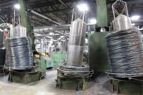 These coils of wire have been dropped onto spindles in preparation for drawing—the process of pulling wire through multiple dies to bring it to the correct diameter. Drawing stretches the wire to many times its original length.