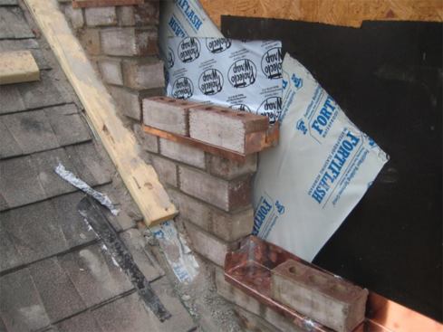 Next, the masons laid in copper pans. A key feature of these pans is the soldered end-dams that direct water onto the front edge of the pan. This hemmed edge extends past the front of the brick about 1/2 to 3/4 inch, providing a lip to which the counterflashing will be attached (by pop-rivets or sheet metal screws). Also note that the builder making the repairs on this job decided to install an additional layer of peel-and-stick flashing lapping into the pan. Though not required, it’s cheap insurance on this costly repair.
