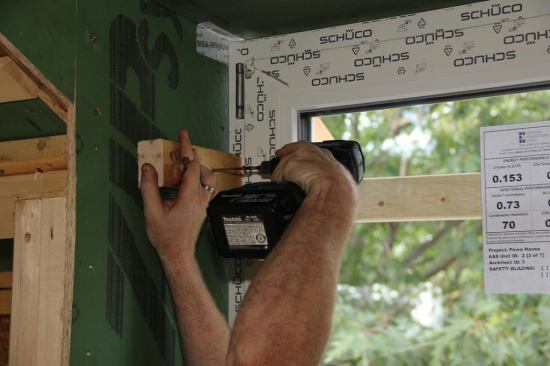Attaching a temporary stop block to the window buck to hold the window steady during leveling, squaring, and fastening.