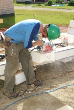 A carpenter trims back the OSB skin of the short panel section in order to allow the piece to fit into place.