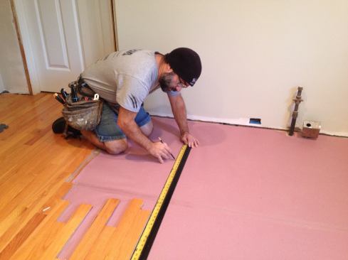 Manny uses a straightedge to extend the line of the existing floor...