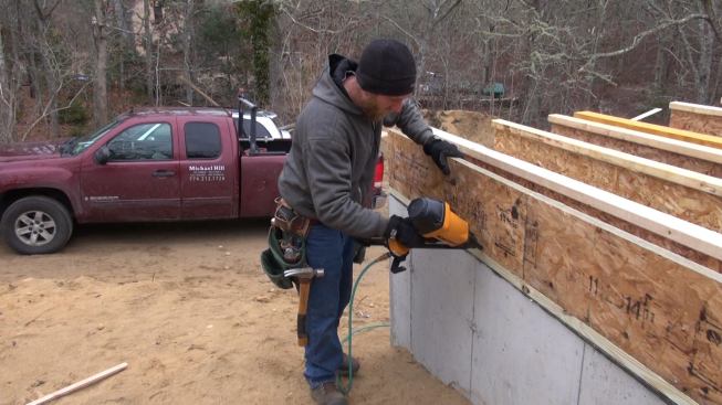 Hill installs an engineered lumber rim joist into the new floor system.