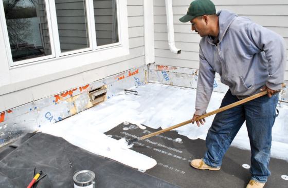 After sweeping the surface clean, the crew applies latex bonding adhesive.