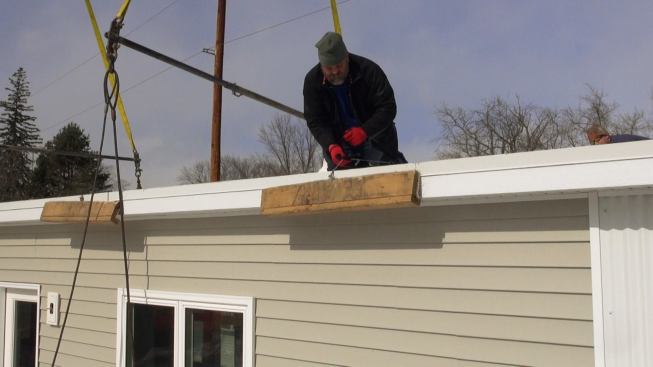 Steve Davis places a protective lumber bumper to keep the lift cables from damaging the brand-new home's eave overhang.