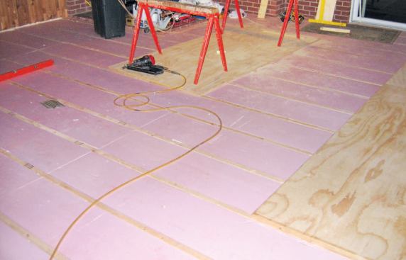 Once stripped of carpeting and tested for moisture, the slab floor of the addition was insulated with XPS foam board fit tightly between lengths of 2-by furring.
