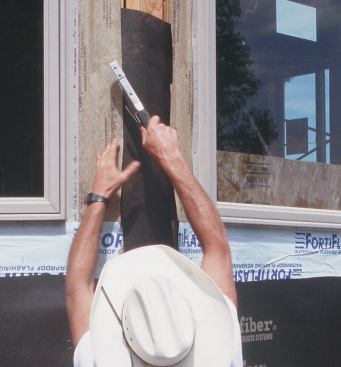 He lays paper under the side window flashings and staples the flashing down before applying membrane to this joint as well.