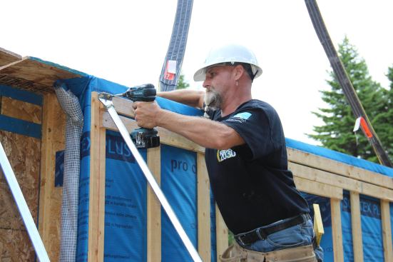 A crew member secures the upper end of an adjustable brace to the wall panel.