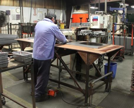 The fellow in this photo is spot-welding a hinge to half of a Storagemaster cover. After spot-welding the hinge to the other half he will send the cover to the weld line for further assembly.
