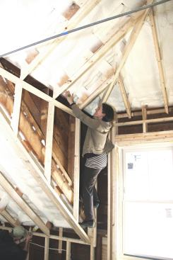 Architect Rachel Conly feels for air leaks near a dormer roof in the home’s second floor living space during blower door testing. The crew found few leaks in the wall system or at joints between the wall and roof systems.