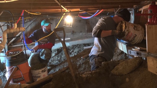 Chris Mitchell pours concrete into the Sonotube for a new foundation pier. Each four-foot tube took about four to six buckets of concrete.