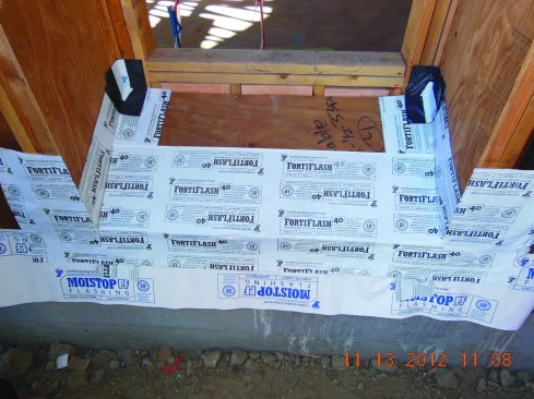 Next, the inner flashing corners are installed with caulk under them. At the front edge of the recess, the author installs a “bridge flashing” spanning between the two flashing strips at the corners.