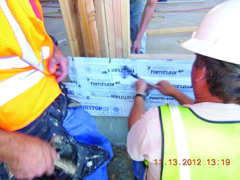 Make two slits at the edge of the opening, and fold the inner tongue of the flashing across the horizontal sill and up the inner face below the window opening, rolling it smooth with a J-roller.