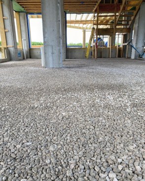 Over the compacted gravel subbase, crushed stone is spread and compacted smooth before the foam is applied.