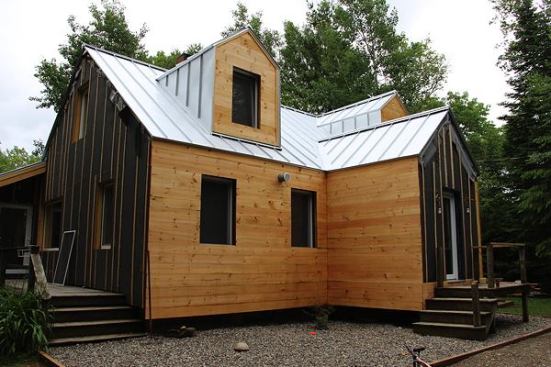 An insulation and window upgrade, topped by a Galvalume roofing and pine board siding facelift (above), will transform the dated exterior into a top-performing, durable, and modern-looking weather envelope.