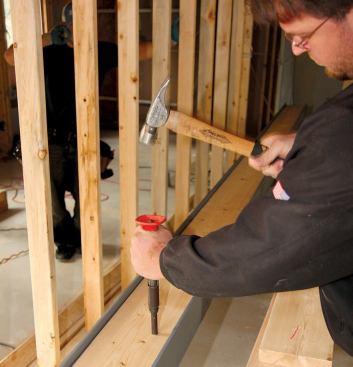 The crew used powder-actuated pins to fasten the 2x8 framing lumber to one side of the web.