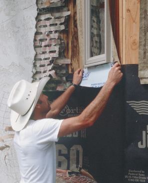 The installer seals the flashing to the paper with adhesive membrane.