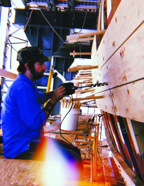 Mystic Seaport shipwright Brett Land drilling holes for trunnels.