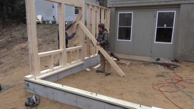 The carpenters set temporary bracing before anchoring the new wall to its foundation sill.