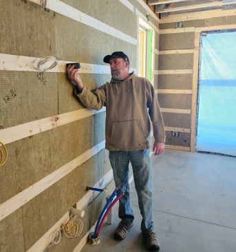 This article is based on the methods specified in ANSI/RESNET/ICC 380, which uses measurements for floor area from the exterior finish of the building. That means the author will need to add the thickness of the exterior walls to measurements like the one he is taking here.