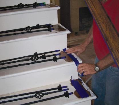 Since the stair parts usually have their final finish when it's time to assemble the balustrade, I retape the drilled treads and mask off the underside of the handrail.