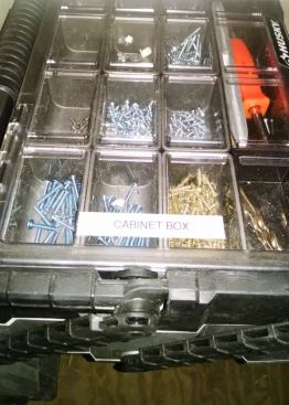 Here’s a closer look at one of boxes below the hoses and cords. This one is a Husky and contains everything needed to install cabinets—including screws, shims, and a screwdriver to adjust hinges.