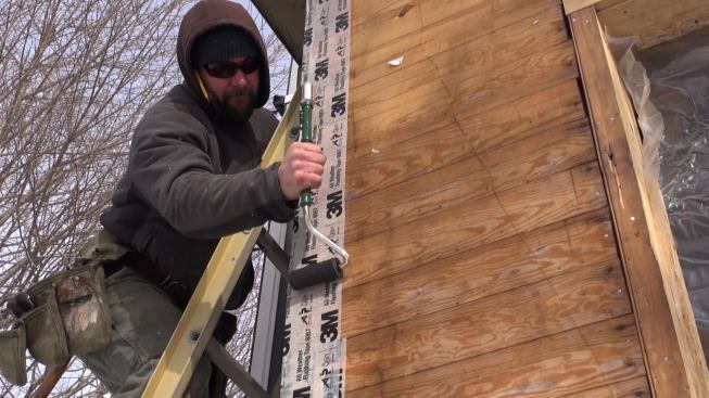 Shane Fenton rolls the 3M tape with a hand roller to help establish good adhesion. The tape grips tenaciously even in cold weather.