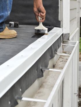 The roof edge is protected with a gutter apron. Glue is applied to the apron.