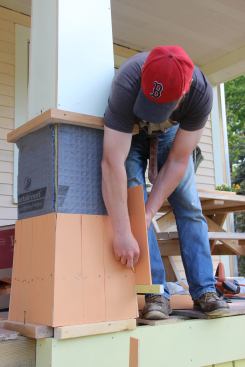 Fenton holds a shingle in place on the post and scribes the back side for a taper cut.
