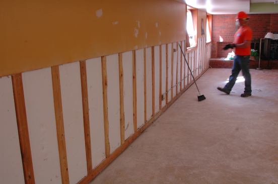 On exterior walls, wet drywall is removed to a height of four feet but furring strips are left to dry in place. After this photo was taken, the beadboard insulation was also removed to aid drying.