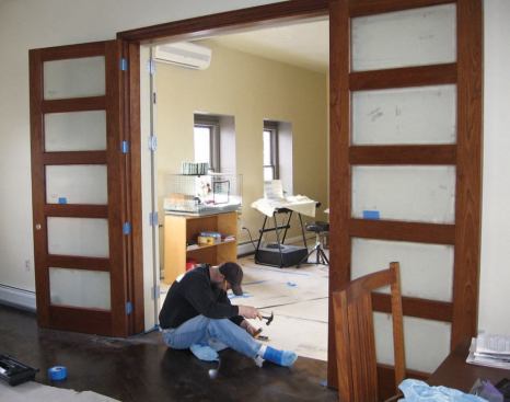 New wood strip flooring running diagonally through the passageway helps tie the two condo units together. The automatic fire doors maintain the integrity of the fire wall, but for daily use the owners rely on a pair of standard French doors hung on the other side of the opening.