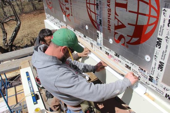 The acrylic adhesive tape is tenacious so care is taken to make sure the flashing is pitched for drainage before being pressed into place. The tape will be pressed into place with a hard rubber j-roller to further increase the bond of the adhesive.