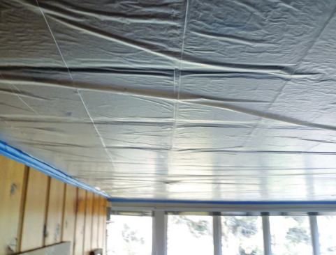 Warm air venting from the attic above sucks a protective plastic sheet against this single-layer T&G ceiling, illustrating its extreme permeability to moving air.
