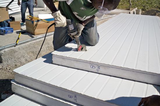 Haitian workers were trained on site to install the steel SIPs, which are made of an EPS core sandwiched between 26-gauge galvanized steel skins. Here, a crew member cuts the gable profile with a Kett panel saw.